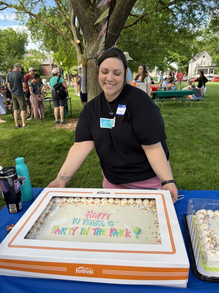 woman next to cake saying happy 10 years of party in the park!